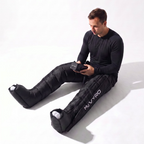 Athlete sitting down wearing MyVYRO Pulse PRO compression boots and holding controller